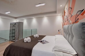 A hotel room with a large bed, a wardrobe, a seating area, and a wall with a floral design. - Boutique Apartment Rebecca with private Garden close to the centre., Lugano, Switzerland (Lugano)