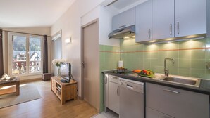 A modern kitchen with a dishwasher, a sink, and a window with a view of houses. - Cham Sud Forclaz504 - 1BR w/ Balcony sleeps 4, Chamonix, France (Chamonix)