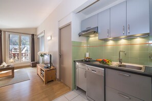A modern kitchen with a dishwasher, a sink, and a window with a view of houses. - Chamonix Sud - Forclaz 504, Chamonix, France (Chamonix)