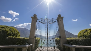 A wrought iron gate with a clear view of a mountainous landscape through it. - Twin Home in Castagnola for 4, Lugano, Switzerland (Lugano)