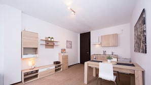 A modern, well-lit room with a wooden desk, white chairs, a small shelf with plants, and a framed picture on the wall. - Twin Home in Castagnola for 4, Lugano, Switzerland (Lugano)