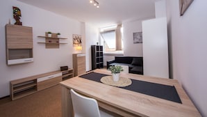 A modern, compact living space with a wooden dining table, a white chair, a black sofa, and a small plant on the table. - Twin Home in Castagnola for 4, Lugano, Switzerland (Lugano)