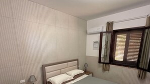 Une chambre moderne avec un lit, des tables de chevet, un bureau avec des serviettes, une lampe et un luminaire au plafond.