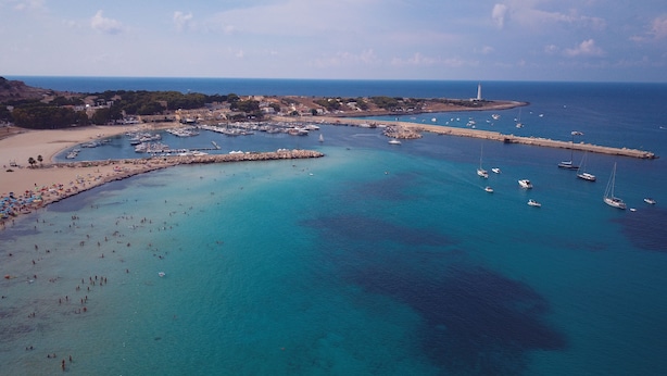 Vue aérienne d’une ville côtière avec un port de plaisance, une plage et un phare.