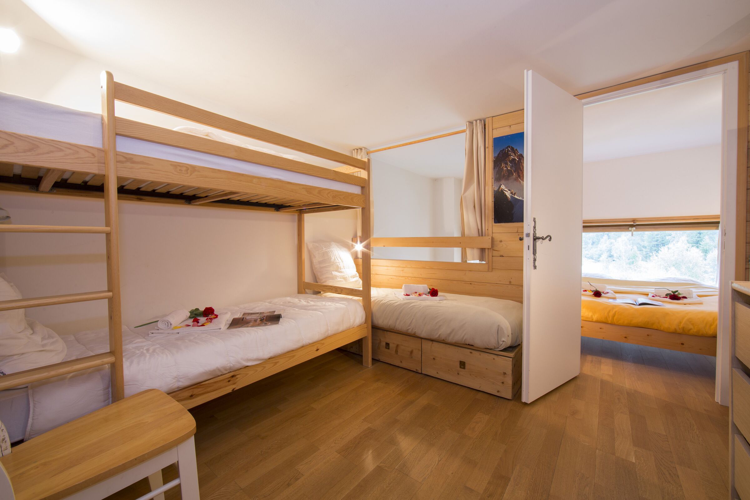 Habitación con literas, piso de madera, un escritorio y una ventana con vistas a montañas.