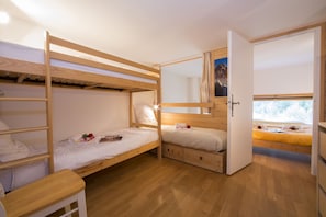 A bunk bed room with a wooden floor, a desk, and a window with a view of mountains. - Grand Roc A220 150m from Slopes, View & Parking, Argentière (Chamonix), France (Argentière (Chamonix))