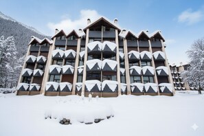 A multi-story hotel with a symmetrical facade, snow-covered balconies, and a mountainous backdrop. - Grand Roc A220 150m from Slopes, View & Parking, Argentière (Chamonix), France (Argentière (Chamonix))