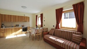 A compact living space with a kitchenette, dining area, and a sofa by a window.