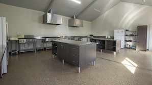 A spacious commercial kitchen with stainless steel appliances, a central island, and ample counter space. - Discovery Parks - Kangaroo Island (Karatta)