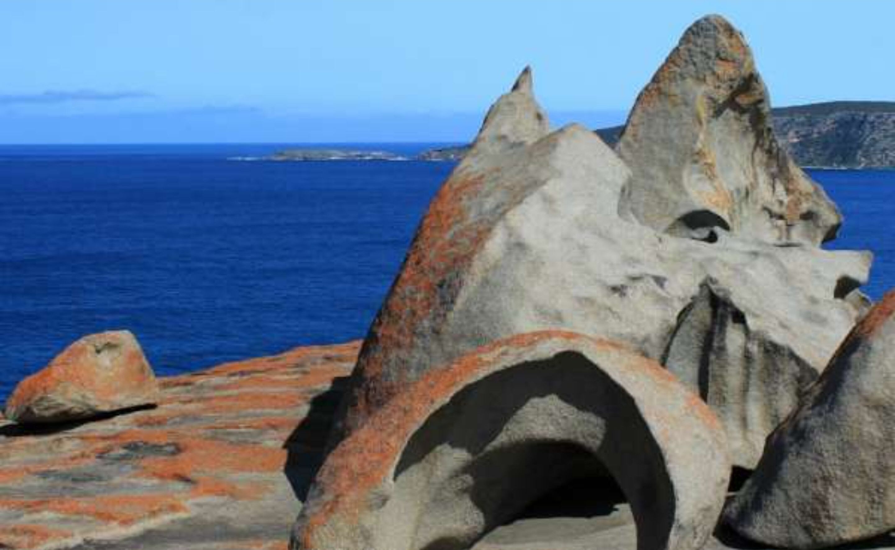Paesaggio costiero con imponenti formazioni rocciose e una limpida vista sul mare.