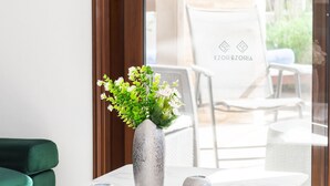 Ein modernes Zimmer mit einem Marmortisch, grünen Polsterstühlen und einer Vase mit Blumen.