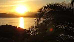 A sunset over a calm body of water with a silhouette of palm trees in the foreground. - Beautiful apartment for two persons with sea view in Trogir near the beach (Trogir)