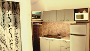 A compact kitchen with a stove, sink, and microwave. - Beautiful apartment for two persons with sea view in Trogir near the beach (Trogir)