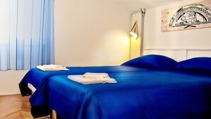A hotel room with two beds, a wooden floor, a wall-mounted lamp, and a painting. - Beautiful apartment for two persons with sea view in Trogir near the beach (Trogir)