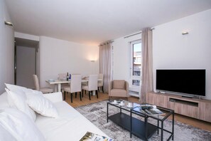 A modern living room with a sofa, coffee table, TV, dining area, and a balcony. - Lugano Motta, Lugano, Switzerland (Lugano)