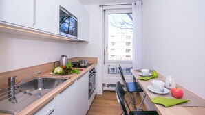Une cuisine moderne équipée d’un évier, d’une cuisinière et d’une fenêtre donnant sur un immeuble.