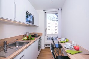 Cozinha moderna com pia, fogão e janela com vista para um edifício.