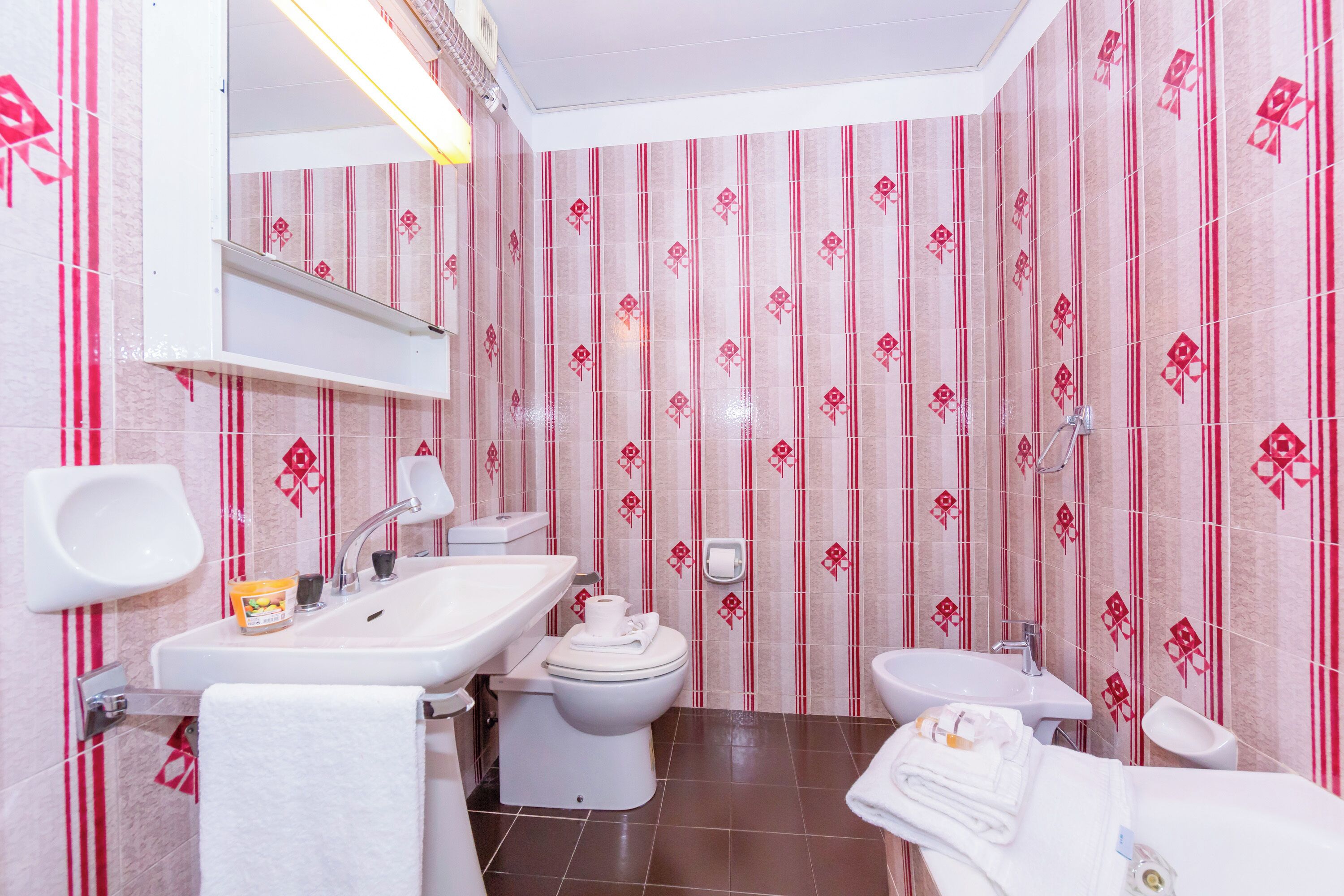 A bathroom with a sink, toilet, bidet, and mirror.