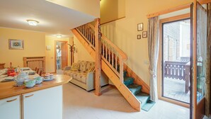 A spacious living area with a wooden staircase, a dining table set with dishes, and a sofa.