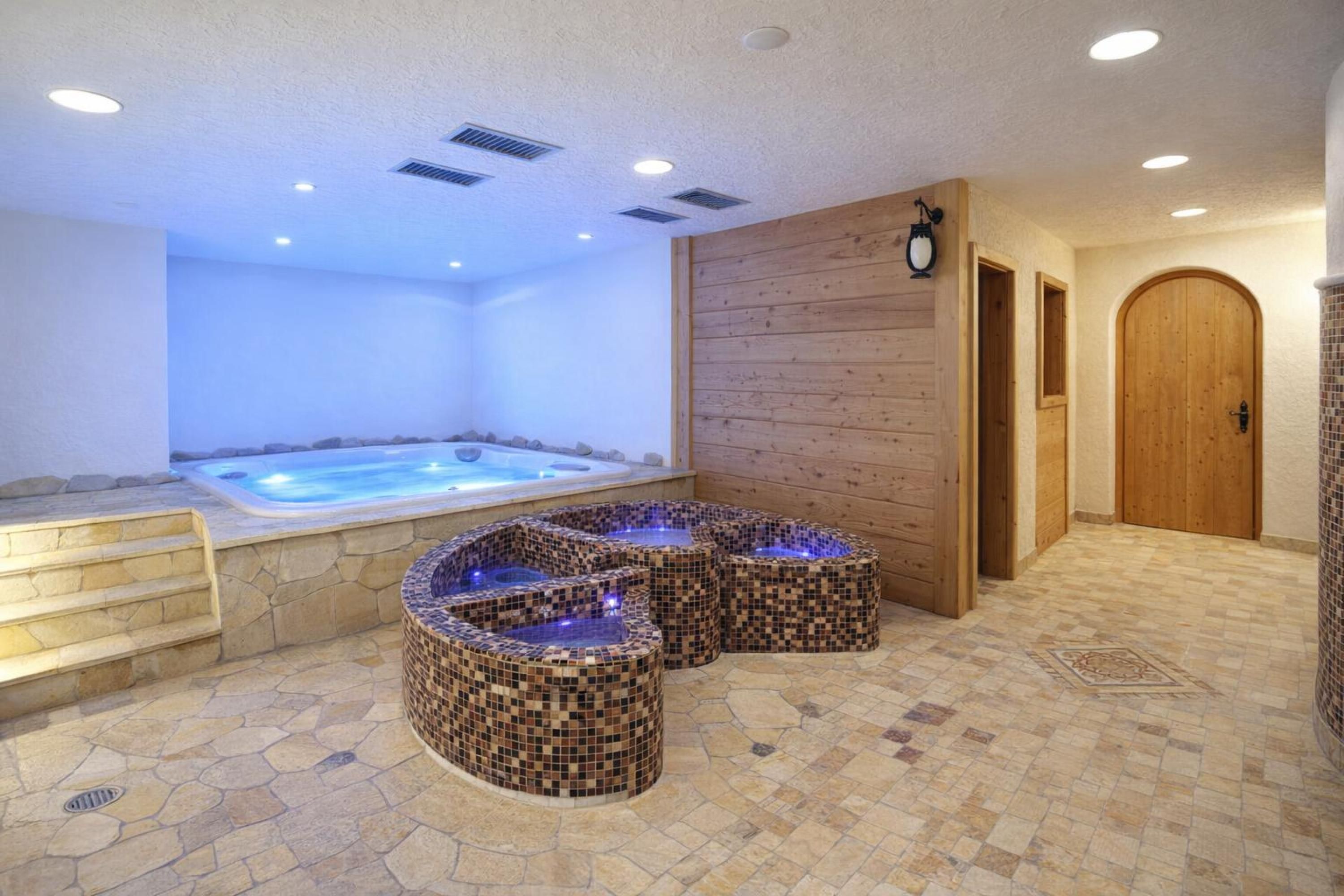 Un espace de détente avec un jacuzzi, des sièges recouverts de mosaïques et une porte en bois.