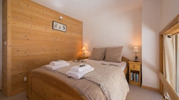 Une chambre à coucher aux murs lambrissés, avec un lit, deux tables de chevet et une petite table de nuit.