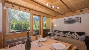 A wooden interior with a dining table set for two, a sofa with patterned cushions, and a framed picture on the wall. - Grand Roc B220 260m from Slopes, View, Parking & WiFi, Argentière (Chamonix), France (Argentière (Chamonix))