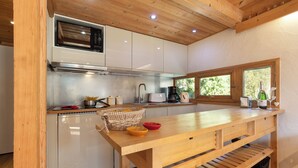 Une cuisine avec des armoires blanches, un plan de travail en bois, un four encastré et une fenêtre.