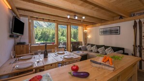 A wooden interior with a dining table set for two, a sofa, and a television on the wall. - Grand Roc B220 260m from Slopes, View, Parking & WiFi, Argentière (Chamonix), France (Argentière (Chamonix))
