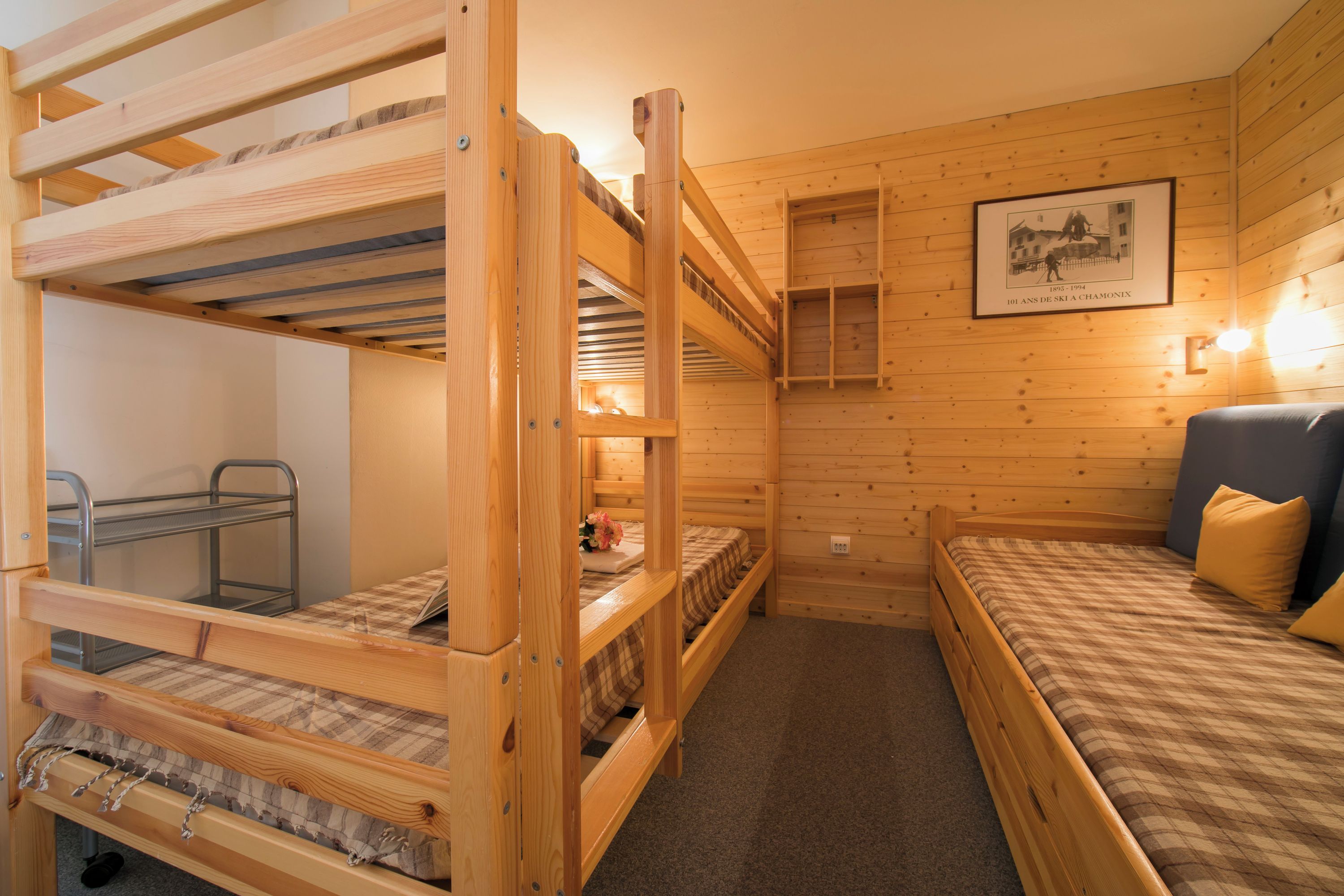 A wooden cabin with bunk beds, a desk, and a framed picture on the wall.
