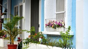 Um edifício com fachada azul e branca, cerca branca de piquete e uma janela com floreira.