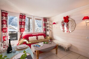 A cozy room with a red sofa, a wooden table with a magazine, and a window with curtains.