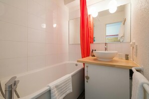 Een badkamer met een bad, een wastafel, een spiegel en een douche.