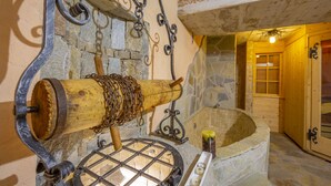 A stone wall with a wooden barrel and metal chains, a stone bathtub, and a wooden door. - Diamante Ski in, Livigno, Italy (Livigno)