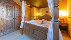 A four-poster canopy bed with a wooden headboard, a nightstand with a bottle and glasses, and a wardrobe with decorative panels. - Diamante Ski in, Livigno, Italy (Livigno)