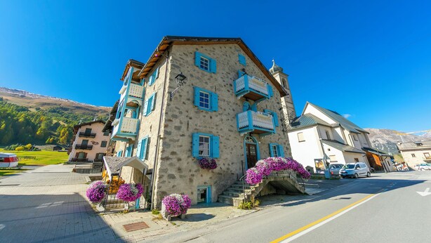 A multi-story building with a stone facade, blue shutters, and balconies. - Diamante Ski in, Livigno, Italy (Livigno)