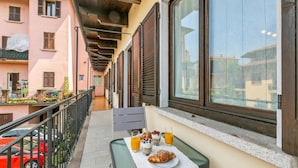 A balcony with a table set for breakfast, including croissants, yogurt, and orange juice.