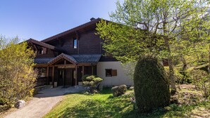 Una casa de madera tradicional con un porche cubierto, un camino de piedra y abundante vegetación.