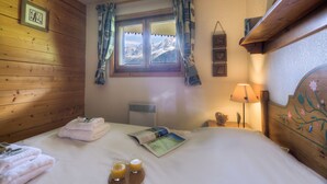 Una habitación con paneles de madera, una cama, toallas y un ventanal con cortinas.