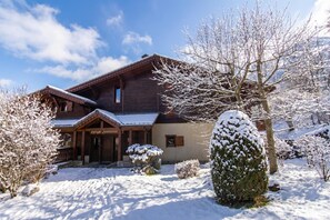Un chalet en bois, avec un toit enneigé, une véranda en bois et une enseigne sur laquelle on peut lire : « Kärfe Bichach ».
