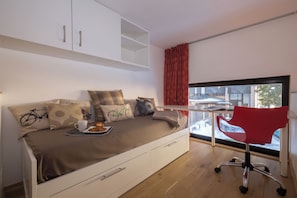 A modern room with a bed, a desk, and a window.