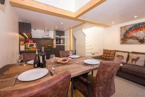 A dining area with a wooden table, leather chairs, and a kitchen in the background.