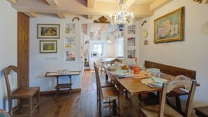 A dining area with a wooden table, chairs, and a chandelier. There are framed pictures on the walls and a door leading to another room. - Antico Chalet, Livigno, Italy (Livigno)