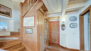 A wooden staircase leading to a room with a bed, a framed picture, and a radiator. - Antico Chalet, Livigno, Italy (Livigno)