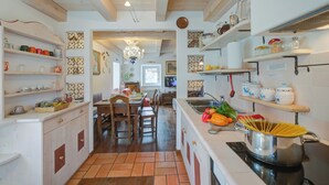 A kitchen with wooden cabinets, a dining area with chairs, and a stove with pasta. - Antico Chalet, Livigno, Italy (Livigno)
