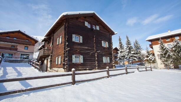 A wooden chalet with a balcony, surrounded by snow-covered trees and other buildings. - Antico Chalet, Livigno, Italy (Livigno)