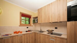 Eine Küche mit Holzausstattung, einer Mikrowelle, einem Spülbecken und einem Fenster mit rotem Vorhang.