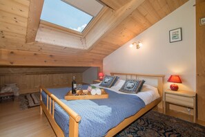 Um quarto aconchegante com teto de madeira, claraboia, cama com bandeja de itens de café da manhã e mesa de cabeceira com abajur.