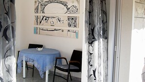 A room with a table and chairs, a wall with artwork, and a door with patterned curtains. - Sea view Apartment in Trogir near the beach (Trogir)