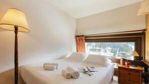 Une chambre d’hôtel avec un lit, une lampe, une table de chevet et une fenêtre donnant sur un beau paysage.
