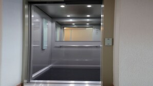 An elevator with a metallic frame, glass panels, and a carpeted floor. - Reno, Livigno, Italy (Livigno)